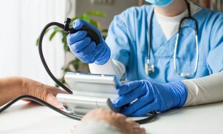 Doctor checking patient blood pressure using manual inflation blood pressure monitor (sphygmomanometer), routine check up to determine systolic and diastolic pressure, hypertension diagnosis treatment